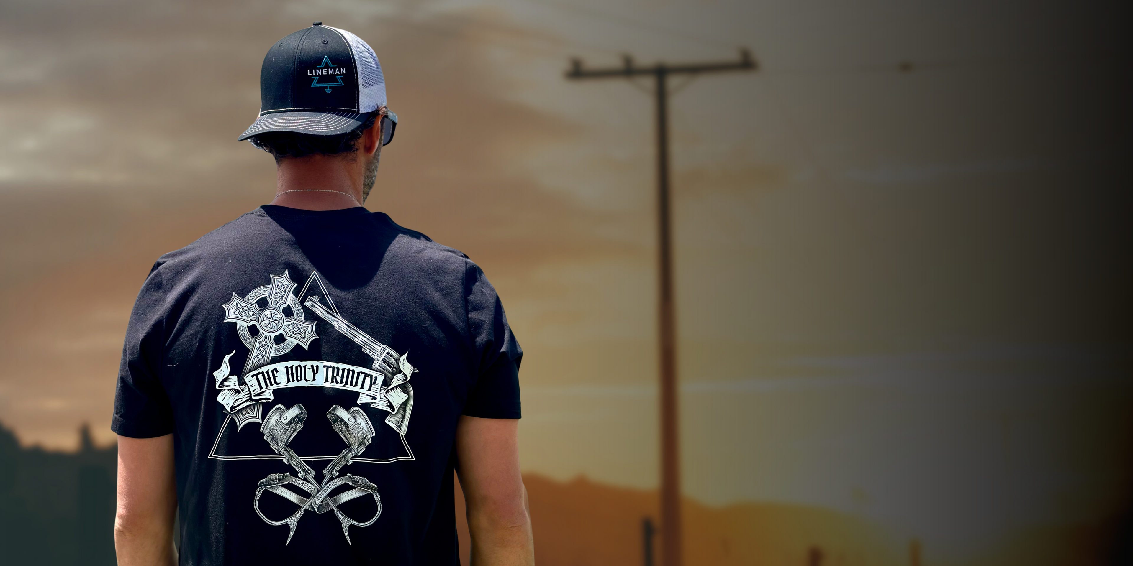 Lineman looking at power pole wearing a lineman hat and lineman shirt.