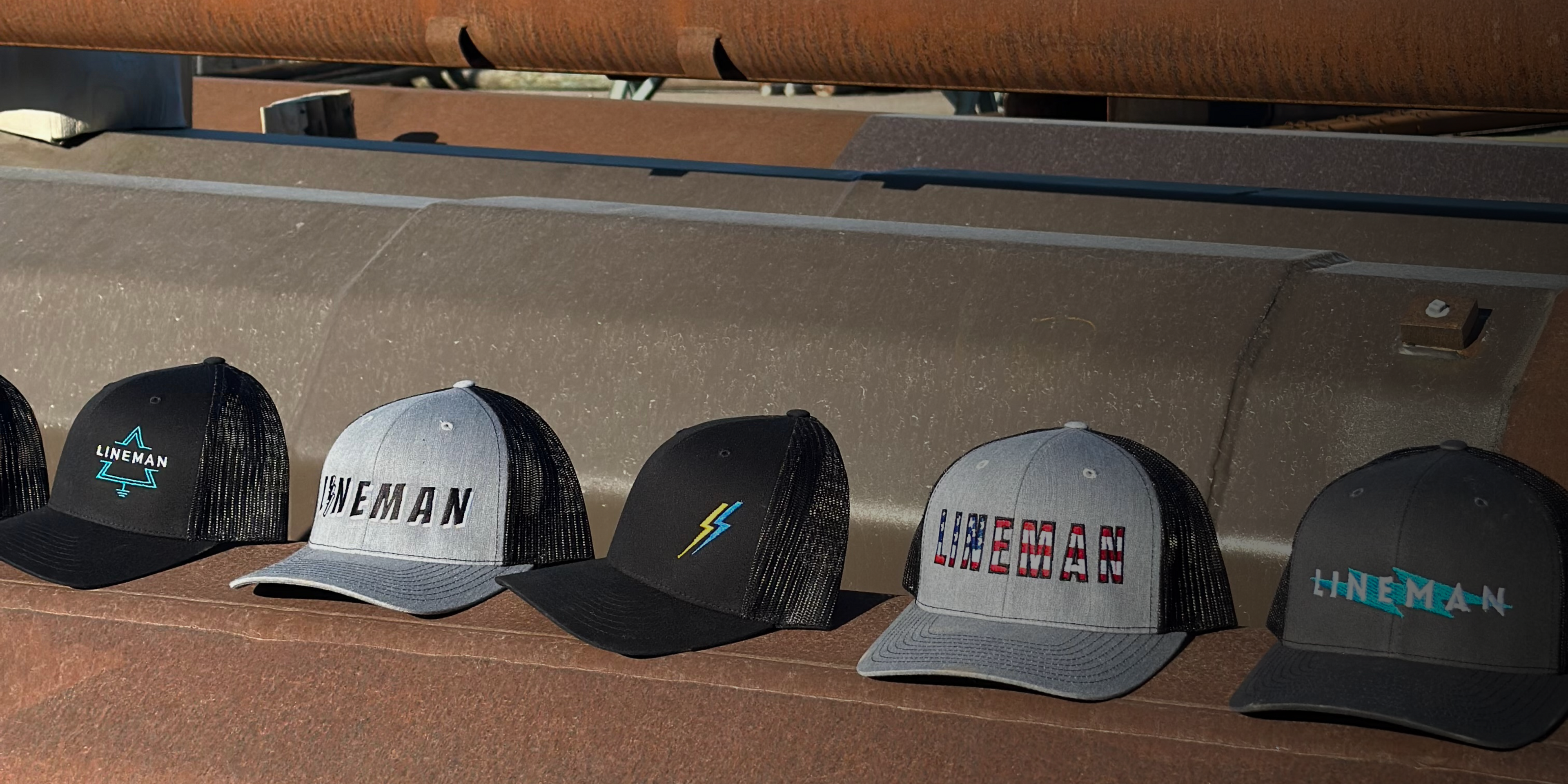 Five ARC Apparel lineman hats on steel power pole.