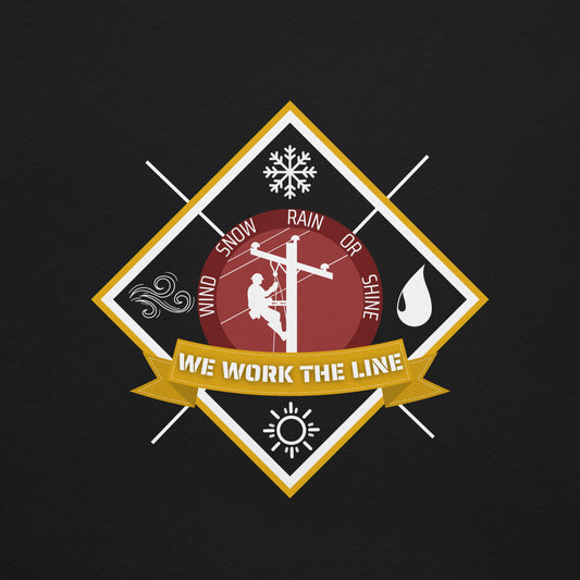 Close up black lineman shirt with 'We Work the Line' badge and icons for wind, rain, snow, and sunshine. Graphic of lineman on power pole.