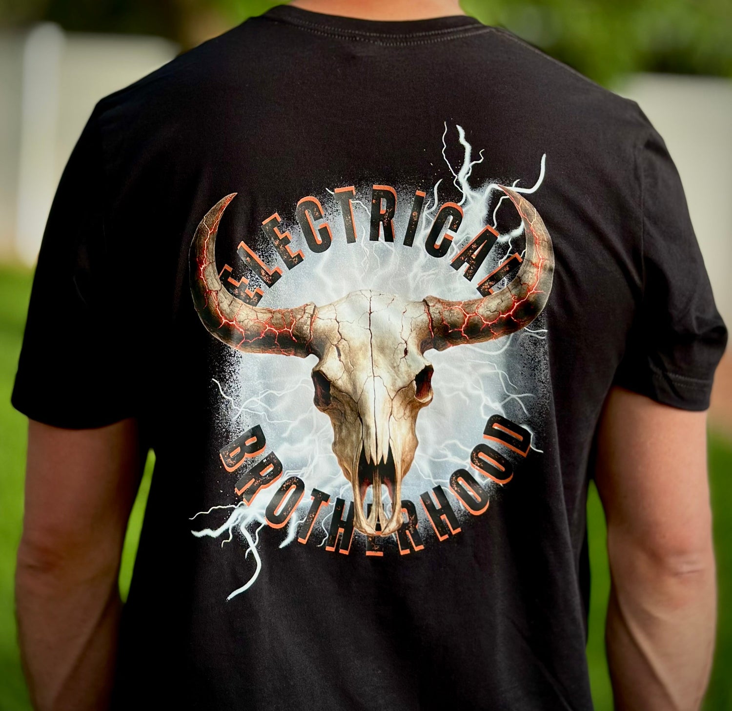 Electrician wearing a black electrician shirt with a bull skull design and 'Electrical Brotherhood' text on the back.