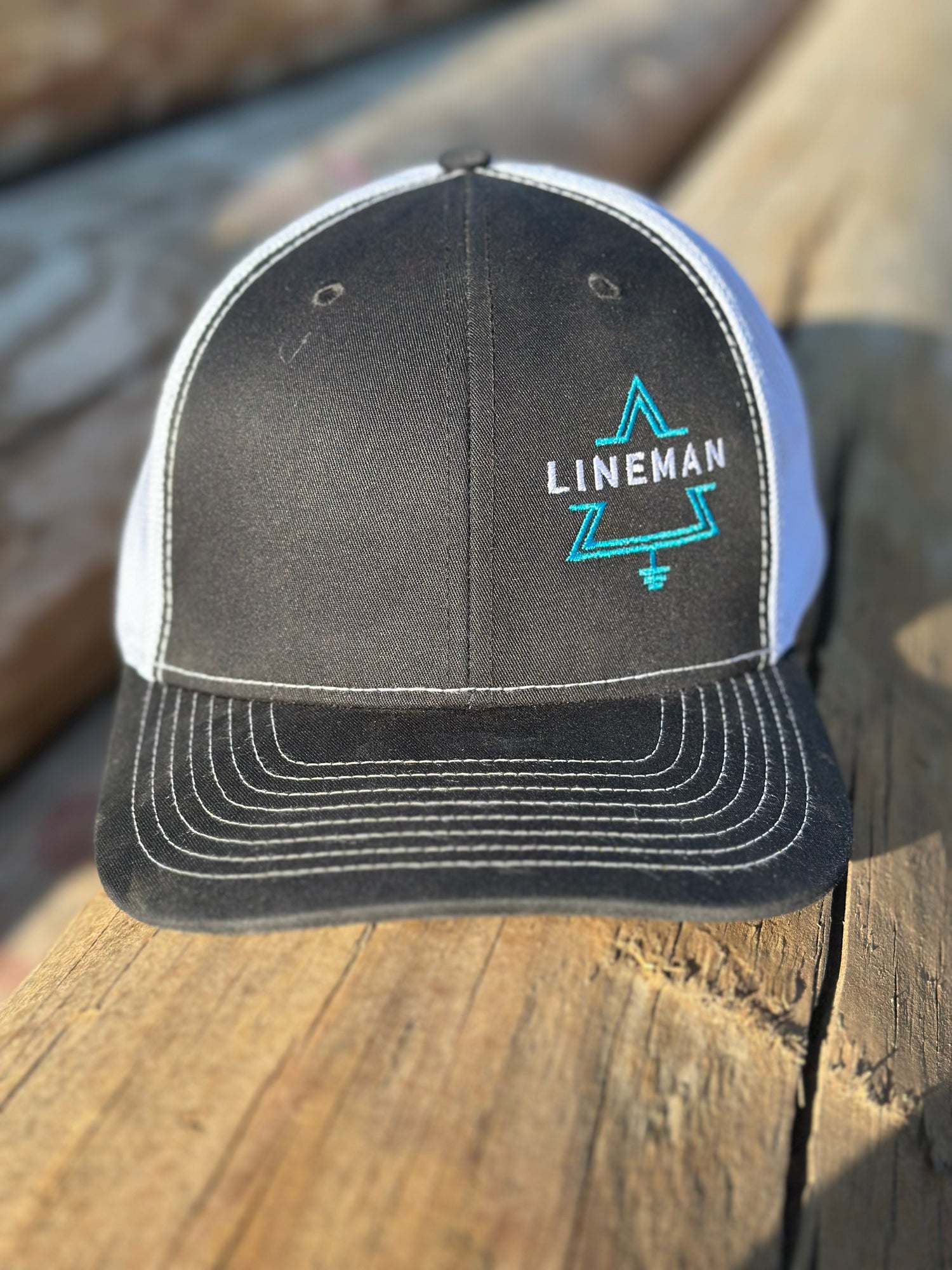 Black and white lineman hat with 'lineman' text inside delta symbol