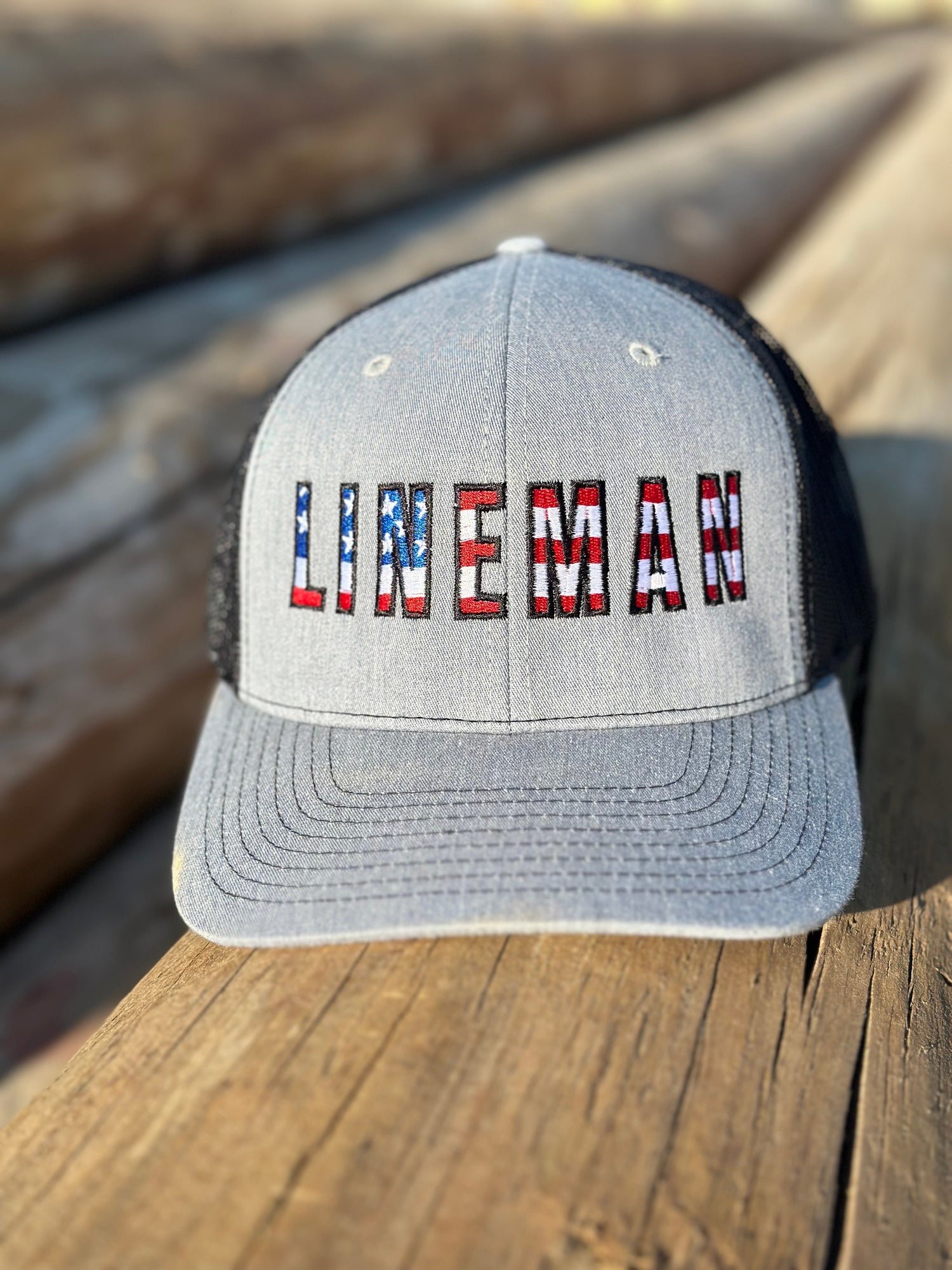 Grey lineman hat with 'lineman' in American flag print on front