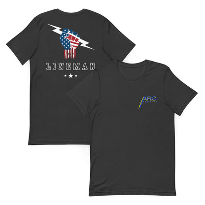 Grey shirt with USA flag fist holding lightning bolt, bold LINEMAN text, and stars underneath. On front ARC Apparel logo.