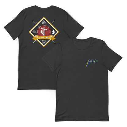 Grey lineman shirt with 'We Work the Line' badge and icons for wind, rain, snow, and sunshine. Graphic of lineman on power pole. Arc apparel logo on front